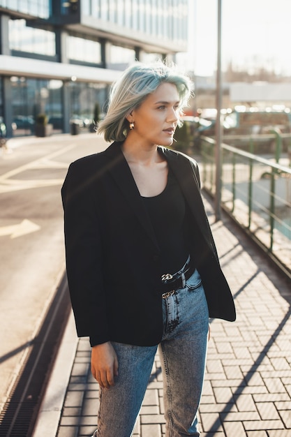 Mulher caucasiana encantadora com cabelo azul posando do lado de fora na rua, olhando para o sol