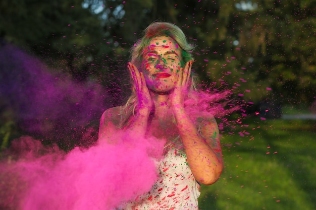 Mulher caucasiana feliz posando com respingos de tinta seca no Festival Holi