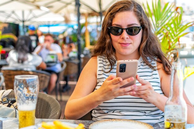 Mulher caucasiana feliz usando telefone inteligente sentado no restaurante