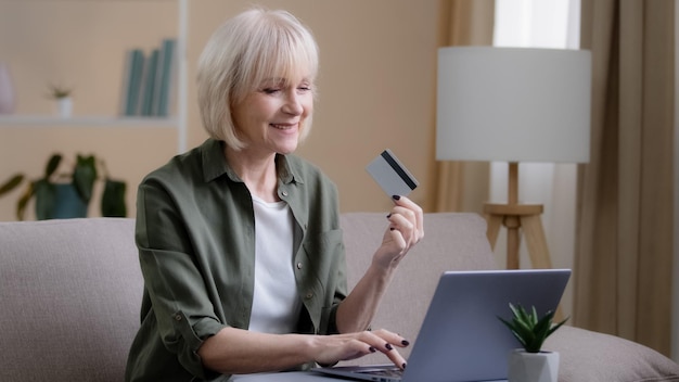 Mulher caucasiana idosa dos anos 60 comprando na internet no laptop em casa Senhora madura adulta sênior ecommerce
