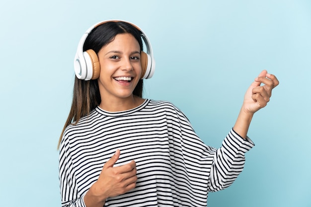 Mulher caucasiana isolada no azul ouvindo música e fazendo gestos de violão