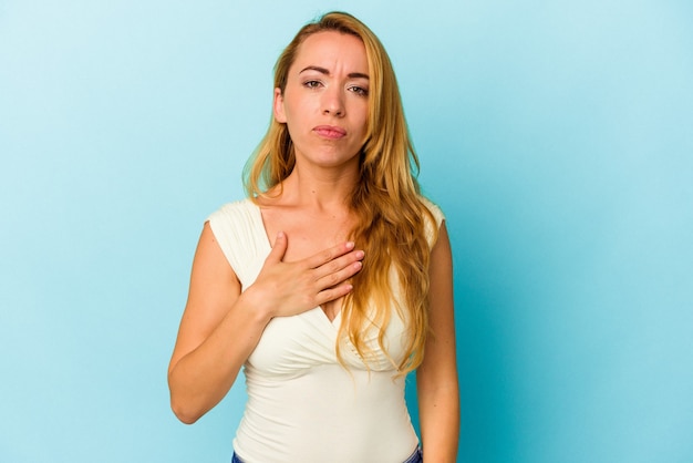 Foto mulher caucasiana isolada sobre fundo azul, fazendo um juramento, colocando a mão no peito.