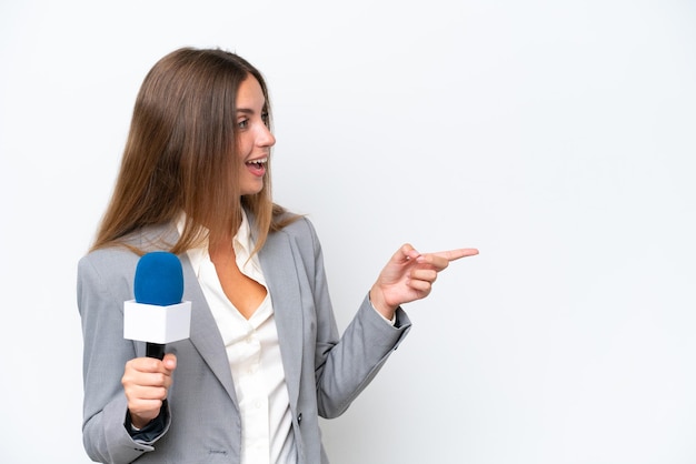 Mulher caucasiana jovem apresentadora de tv isolada no fundo branco, apontando o dedo para o lado e apresentando um produto