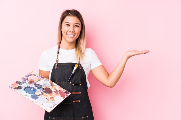 Mulher caucasiana jovem artista segurando uma paleta mostrando um espaço em branco