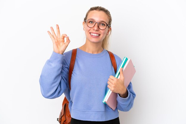 Mulher caucasiana jovem estudante isolada no fundo branco, mostrando sinal de ok com os dedos