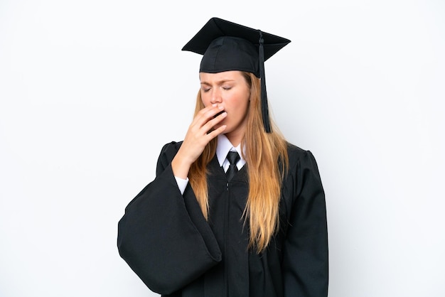 Mulher caucasiana jovem graduada na universidade isolada em fundo branco bocejando e cobrindo a boca aberta com a mão