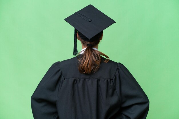 Mulher caucasiana jovem graduada universitária sobre fundo isolado na posição traseira