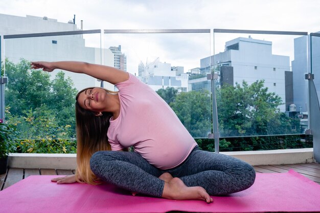 Mulher caucasiana jovem grávida em casa esticando e praticando ioga