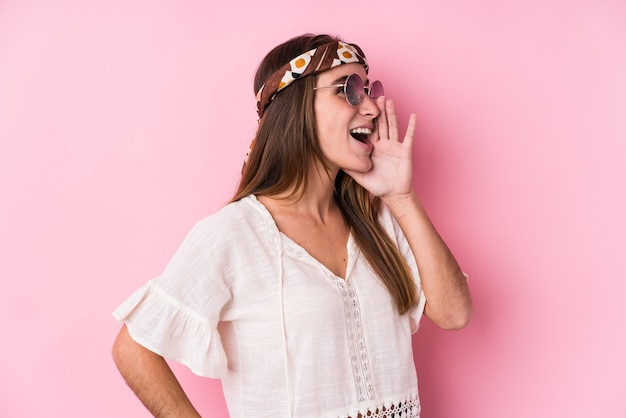 Mulher caucasiana jovem hippie isolada gritando e segurando a palma da mão perto da boca aberta.