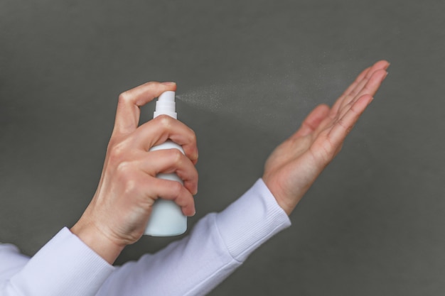 Foto mulher caucasiana limpa as mãos com um spray para lavar as mãos à base de álcool. medidas preventivas contra infecções com gel desinfetante antibacteriano para as mãos.