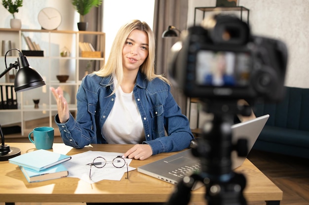 Mulher caucasiana loira feliz em camisa jeans gravando tutorial online