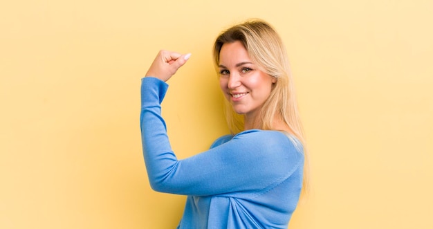 Mulher caucasiana loira se sentindo feliz, satisfeita e poderosa, com ajuste de flexão e bíceps musculosos, parecendo forte depois da academia