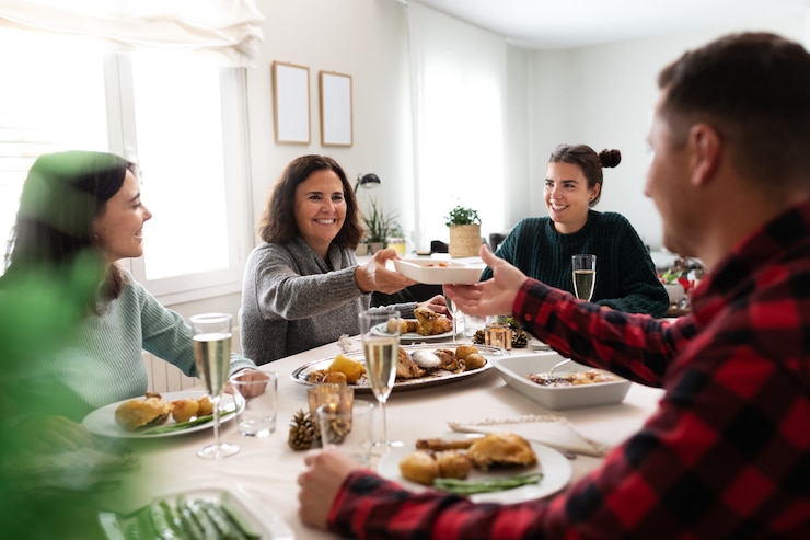 Foto mulher caucasiana madura passando o prato de comida para o jovem durante o jantar de natal em família.