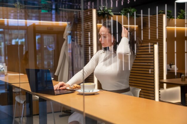 Foto mulher caucasiana no café, trabalhando no laptop e bebendo café.