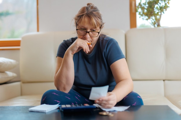 Foto mulher caucasiana preocupada e desesperada calculando despesas domésticas fazendo papelada e contas bancárias contabilizando com calculadora sofrendo estresse em problemas financeiros e depressão