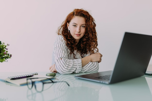 Mulher caucasiana ruiva digitando no laptop enquanto está sentada na mesa em casa mulher de negócios tecnologia da internet trabalhando remotamente
