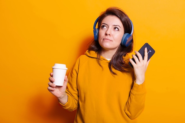 Mulher caucasiana segurando um smartphone e uma xícara de café