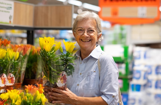 Mulher caucasiana sênior no supermercado selecionando uma planta de flores amarelas em oferta especial atenta ao aumento de preços e inflação