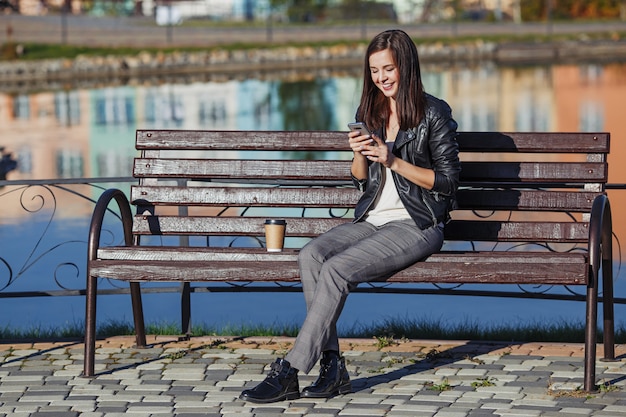 Mulher caucasiana sorridente com telefone móvel, sentado no parque