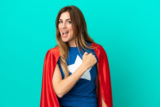 Mulher caucasiana super-heroína isolada em um fundo azul comemorando uma vitória