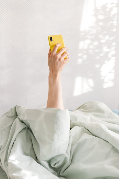 Mulher caucasiana usando smartphone na cama