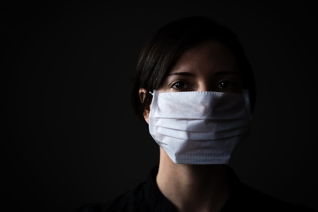 Mulher caucasiana, vestindo uma máscara médica branca para proteção contra coronavírus