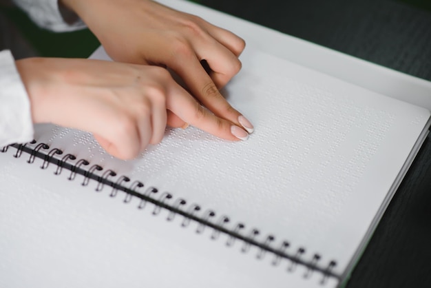 Mulher cega lê livro escrito em Braille Feche o toque do dedo no código braille