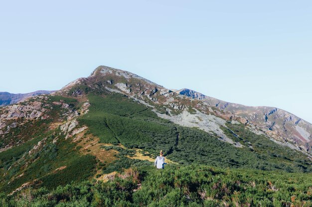 Mulher cercada pela natureza caminhando pela montanha