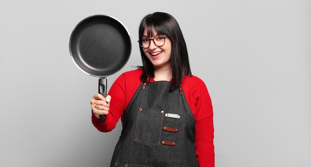 mulher chef bonita de tamanho grande cozinhando com uma panela