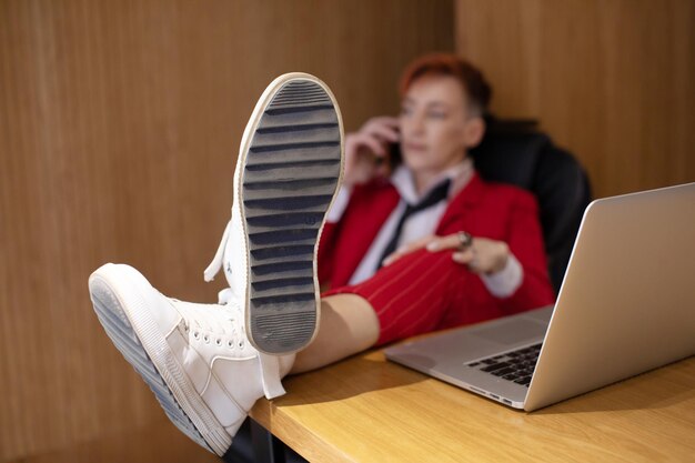 Mulher chefe descansando no trabalho mulher de negócios usando telefone e pés na mesa