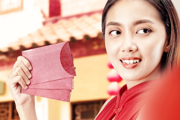 Mulher chinesa asiática em um vestido cheongsam segurando envelopes vermelhos. Feliz Ano Novo Chinês