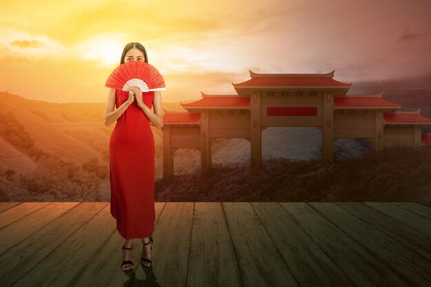 Mulher chinesa asiática em um vestido cheongsam segurando fã celebra o ano novo chinês. Feliz Ano Novo Chinês