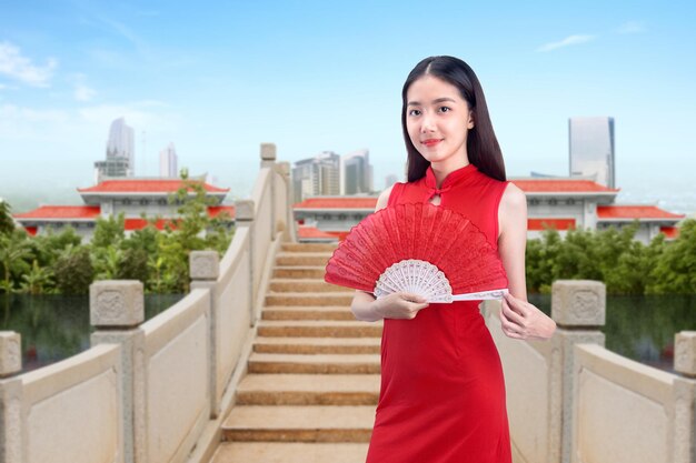 Mulher chinesa asiática em um vestido cheongsam segurando fã celebra o ano novo chinês. Feliz Ano Novo Chinês