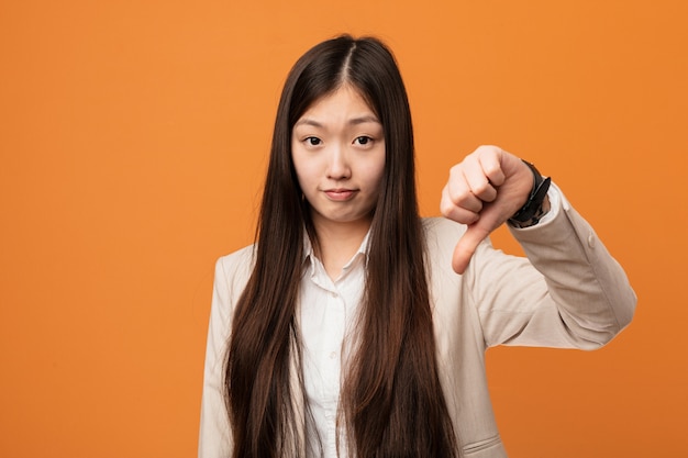 Mulher chinesa de negócios jovem mostrando um gesto de antipatia, polegares para baixo. conceito de desacordo.
