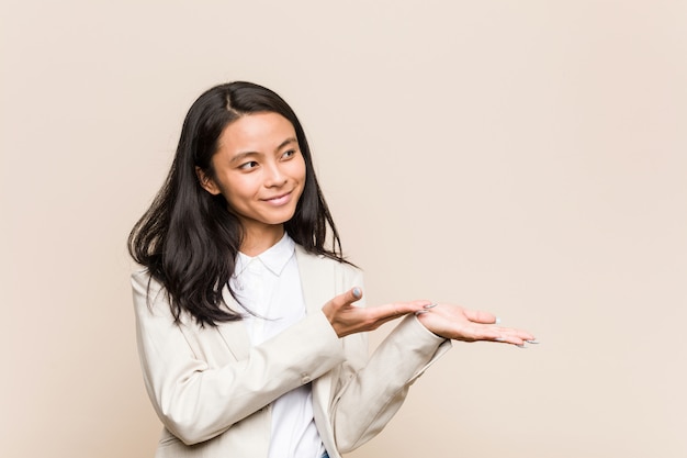 Mulher chinesa de negócios jovem segurando um espaço de cópia na palma da mão.