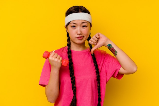 Mulher chinesa jovem esporte mostrando um gesto de antipatia, polegares para baixo. Conceito de desacordo.