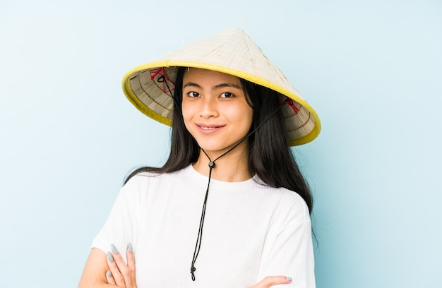 Mulher chinesa nova que veste um feno vietnamiano que mostra um gesto do desagrado, polegares para baixo.