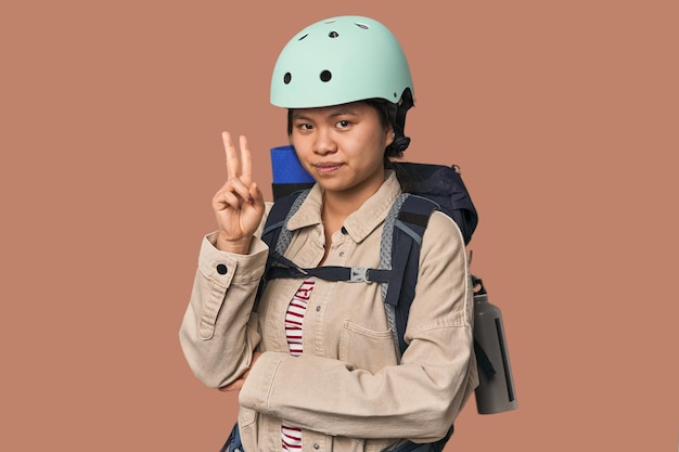 Mulher chinesa preparada para atividades de montanha mostrando o número dois com os dedos