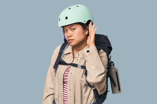 Mulher chinesa preparada para atividades de montanha tentando ouvir uma fofoca