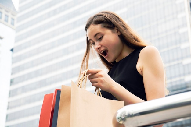 Foto mulher chocada olhando para sacos de compras na cidade