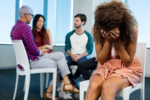 Foto mulher chorando enquanto equipe de negócios criativos atrás do escritório