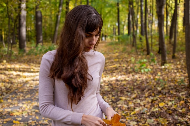 Mulher chorando triste no parque. jovem mulher bonita com folha de outono no parque outono, sob o sol brilha