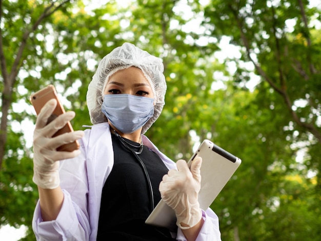 Mulher cientista enfermeira olhando para smartphone tablet celular pesquisa documento de informação relatório ecologia natural ambiente natural tecnologia teste médico cuidados de saúde agricultura