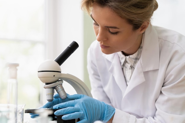 Mulher cientista está usando microscópio em um laboratório durante a pesquisa