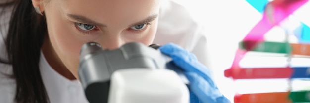 Mulher cientista olhando através de um microscópio estudando DNA