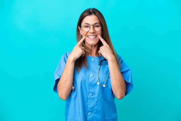 Mulher cirurgiã de meia idade isolada em fundo azul sorrindo com uma expressão feliz e agradável