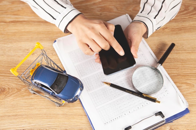 Mulher clica na tela do smartphone. conceito de venda de carro. carro no carrinho