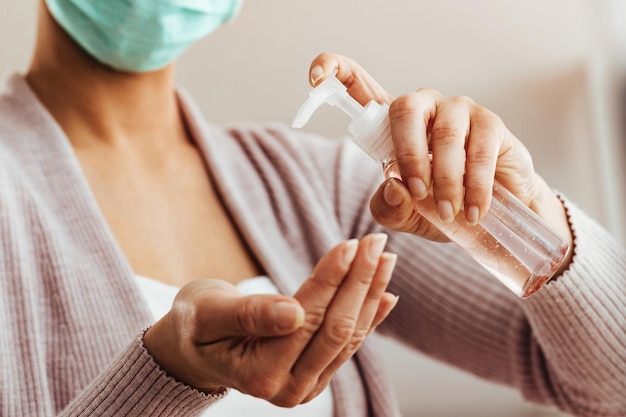 Foto mulher closeup desinfetando as mãos com gel antibacteriano em casa