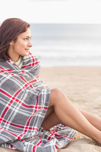 Mulher coberta com cobertor na praia