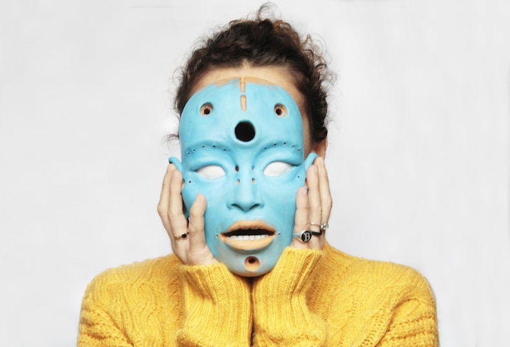 Foto mulher cobre o rosto com uma máscara azul artística